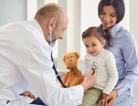 Pediatric specialist consulting with a child and parent during a routine health checkup for growth, development, and preventive care.